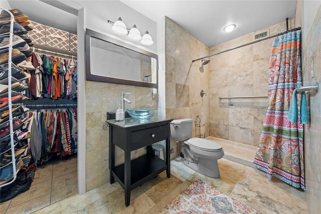 bathroom featuring toilet, tile walls, tiled shower, and vanity