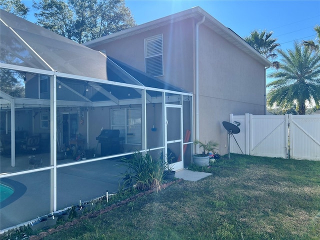 view of side of property with a pool, a yard, a patio, and glass enclosure