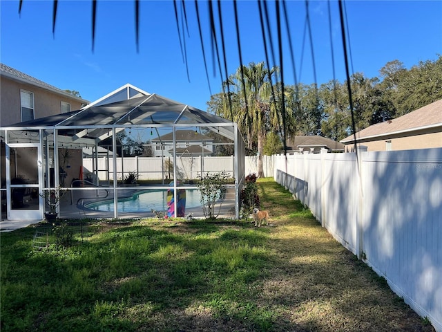 view of yard with a fenced in pool and glass enclosure