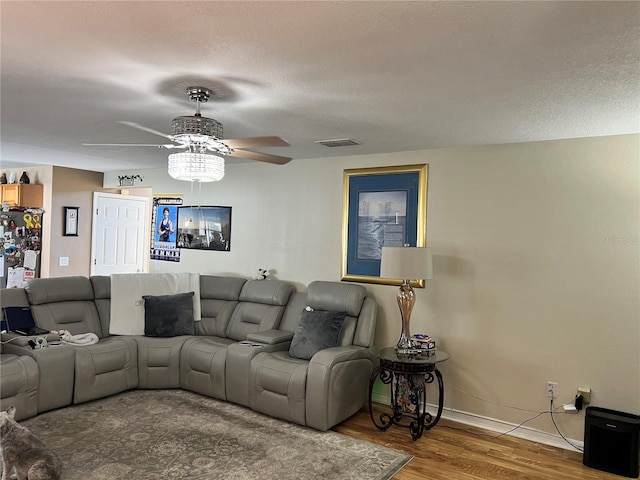 living room featuring hardwood / wood-style flooring, ceiling fan, and a textured ceiling