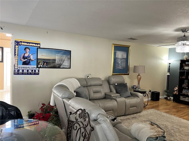 living room featuring hardwood / wood-style flooring, ceiling fan, and a textured ceiling