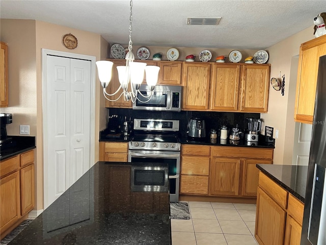 kitchen with decorative backsplash, hanging light fixtures, light tile patterned floors, stainless steel appliances, and a textured ceiling