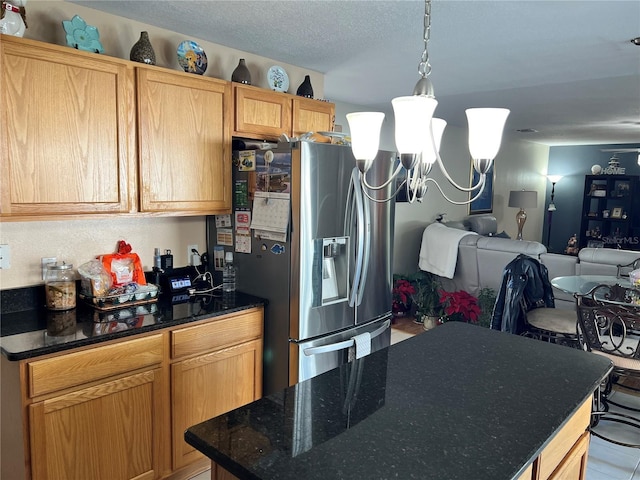 kitchen with decorative light fixtures, stainless steel fridge, a textured ceiling, and a kitchen island