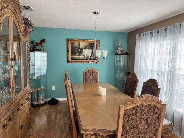 dining space featuring dark hardwood / wood-style flooring, a chandelier, and a textured ceiling