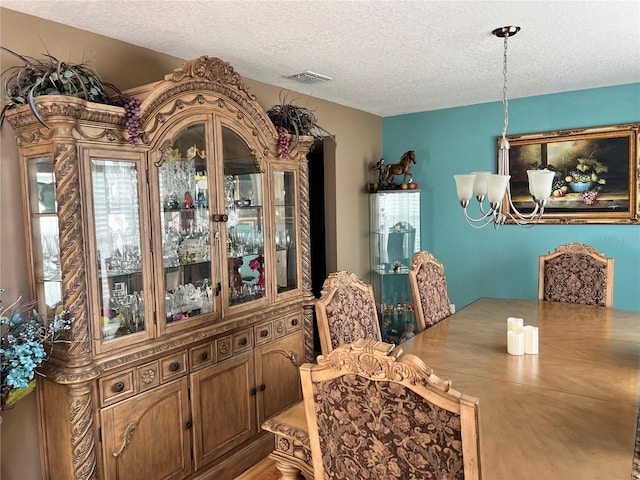 dining area with an inviting chandelier and a textured ceiling