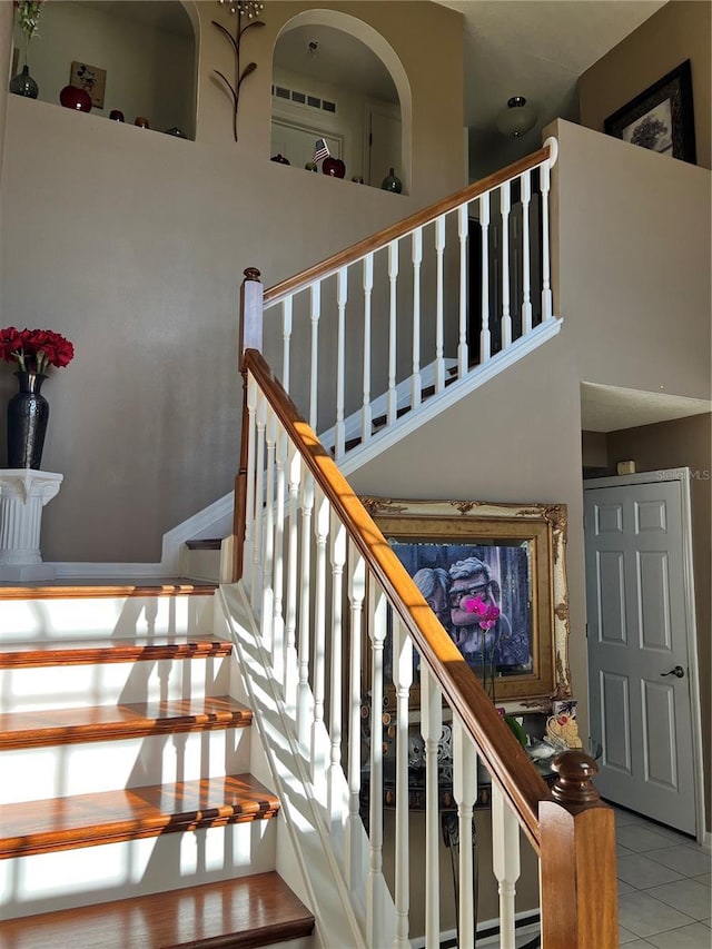 stairway featuring tile patterned floors and a high ceiling