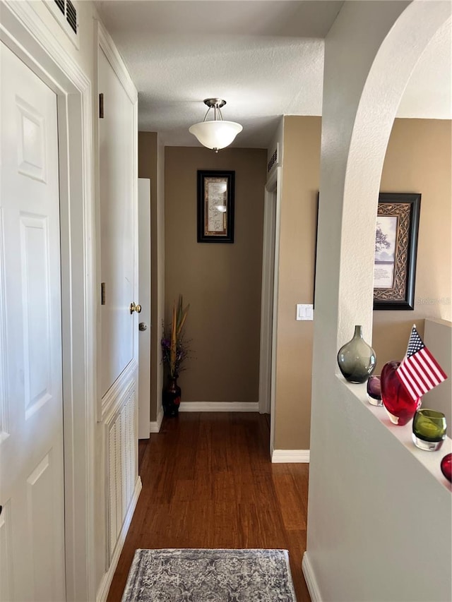 hall featuring dark wood-type flooring and a textured ceiling