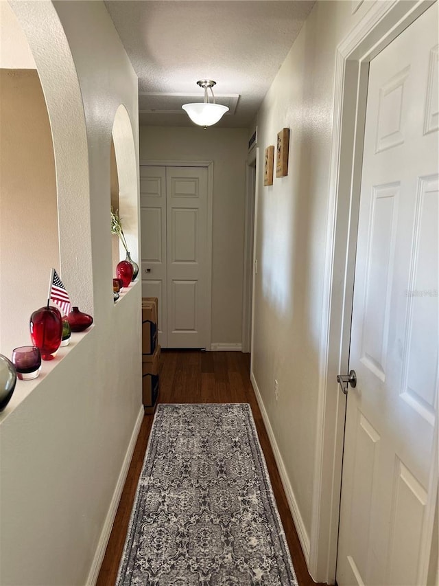 corridor featuring dark wood-type flooring and a textured ceiling