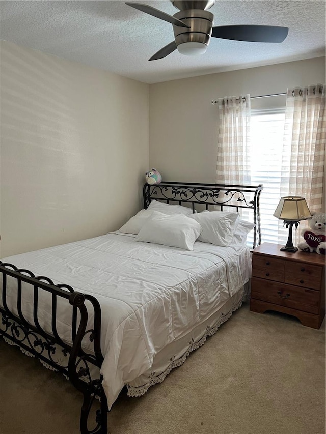 bedroom with ceiling fan, carpet floors, and a textured ceiling