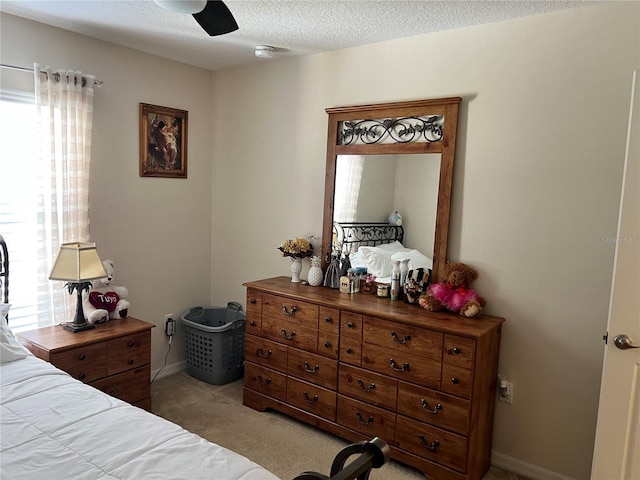 bedroom with a textured ceiling, light colored carpet, and ceiling fan