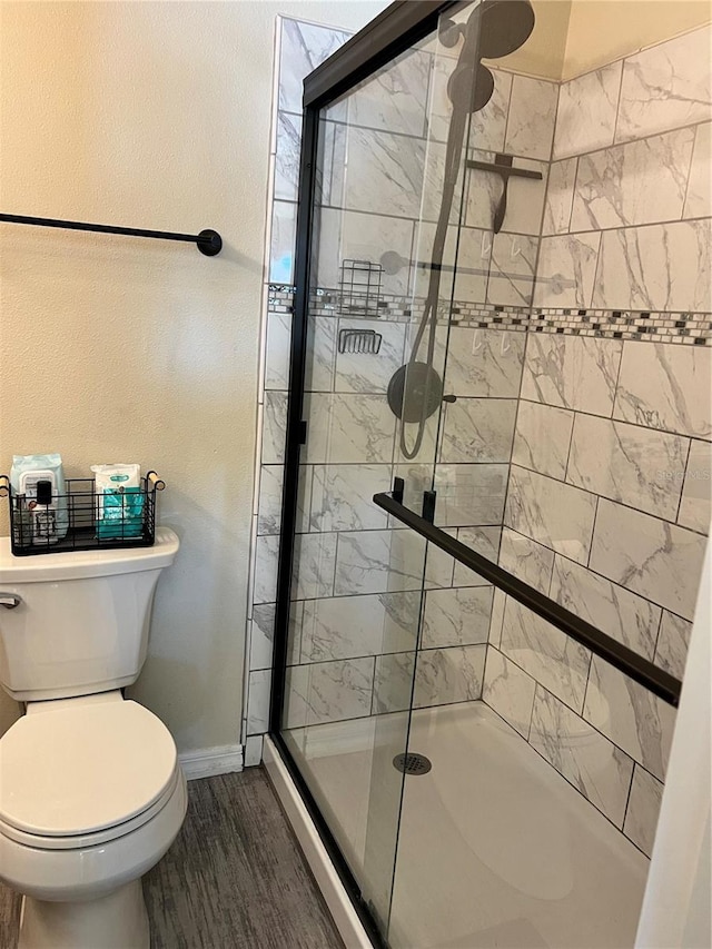 bathroom with an enclosed shower, wood-type flooring, and toilet