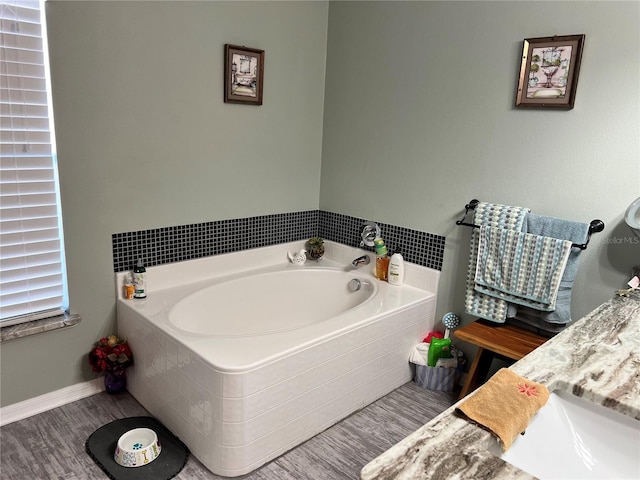 bathroom featuring hardwood / wood-style floors, vanity, and tiled bath