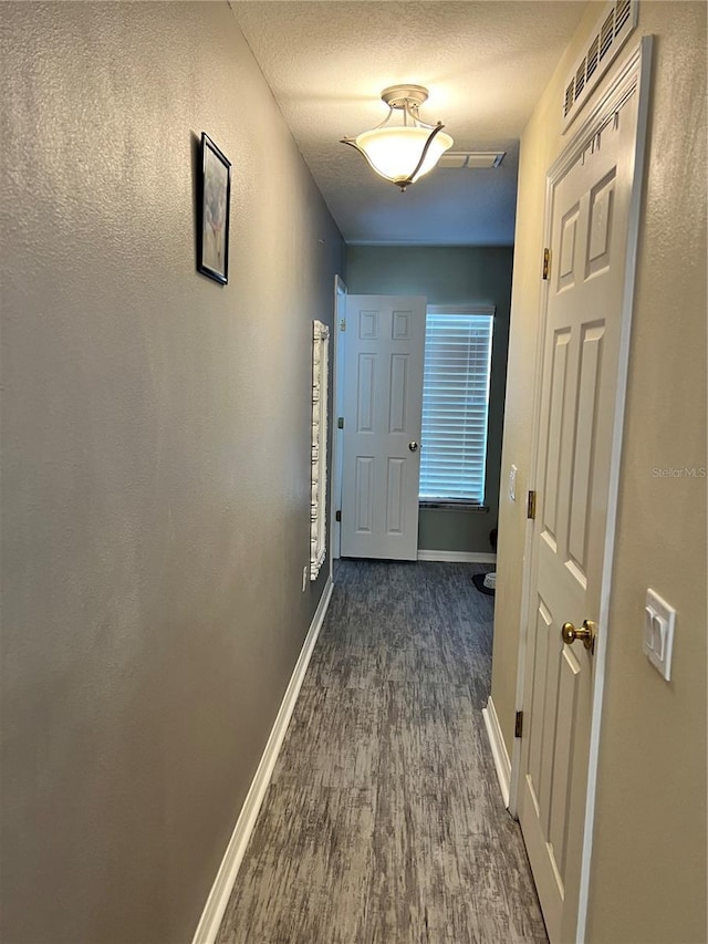 hall featuring dark hardwood / wood-style floors and a textured ceiling