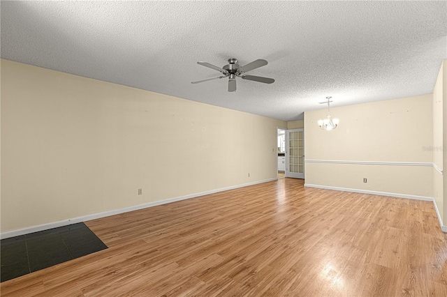 spare room featuring ceiling fan with notable chandelier, a textured ceiling, and light wood-type flooring