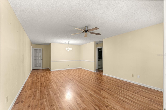 empty room featuring a textured ceiling, ceiling fan with notable chandelier, and light hardwood / wood-style flooring