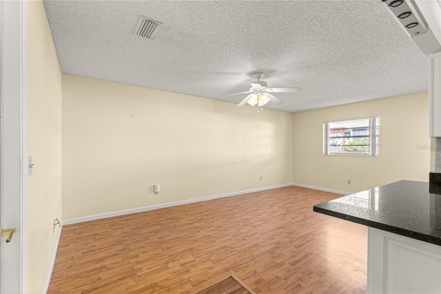 unfurnished living room featuring ceiling fan, a textured ceiling, and light hardwood / wood-style flooring