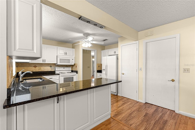 kitchen featuring kitchen peninsula, decorative backsplash, white appliances, white cabinets, and sink