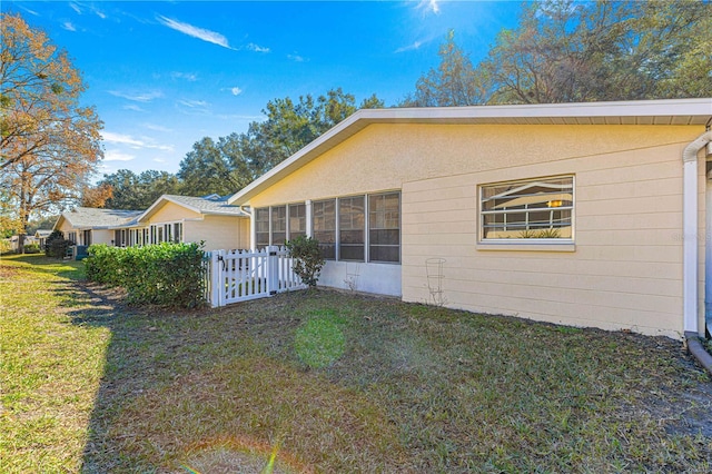 view of side of property with a lawn and a sunroom