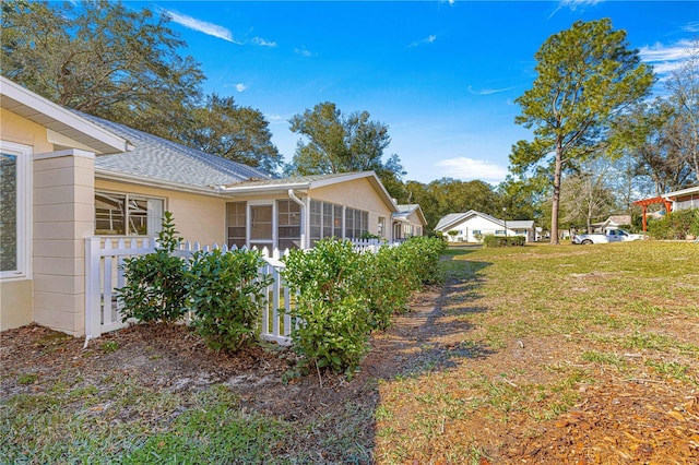 view of property exterior with a sunroom and a lawn