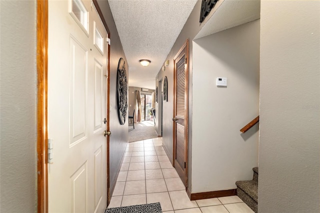 hallway featuring light tile patterned floors and a textured ceiling