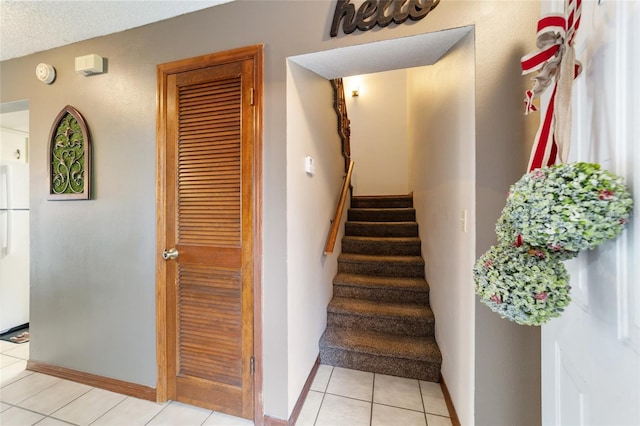 stairs with a textured ceiling and tile patterned floors