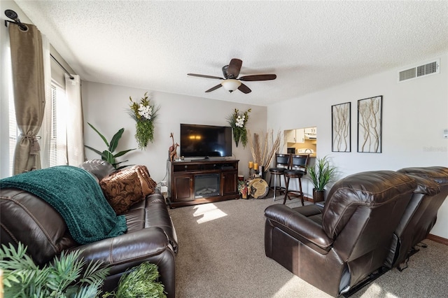 living room with carpet, ceiling fan, and a textured ceiling