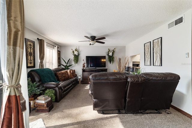 carpeted living room featuring ceiling fan and a textured ceiling