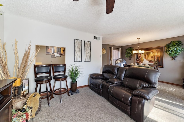 living room with ceiling fan with notable chandelier, a textured ceiling, and carpet flooring