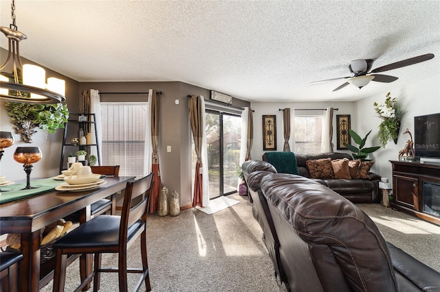 living room with ceiling fan with notable chandelier, a textured ceiling, and light carpet