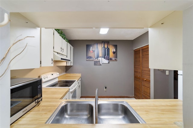 kitchen featuring white range with electric cooktop, sink, and white cabinetry