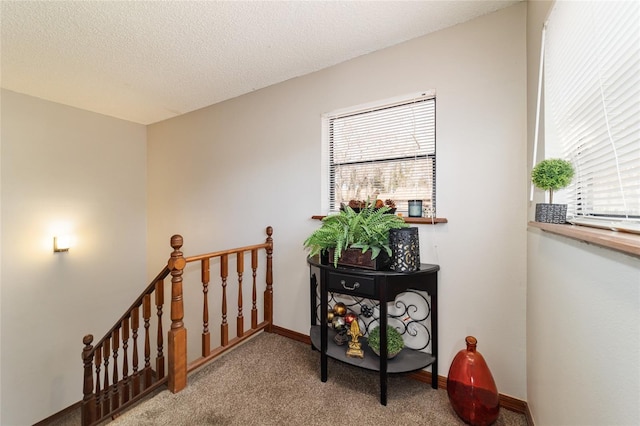 hallway with light carpet and a textured ceiling