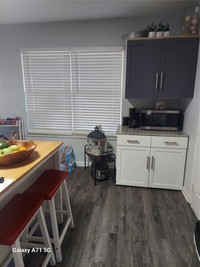 kitchen with dark hardwood / wood-style floors, white cabinets, and light stone counters