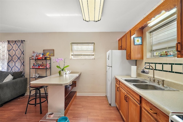 kitchen with a kitchen breakfast bar, light wood-type flooring, sink, and range