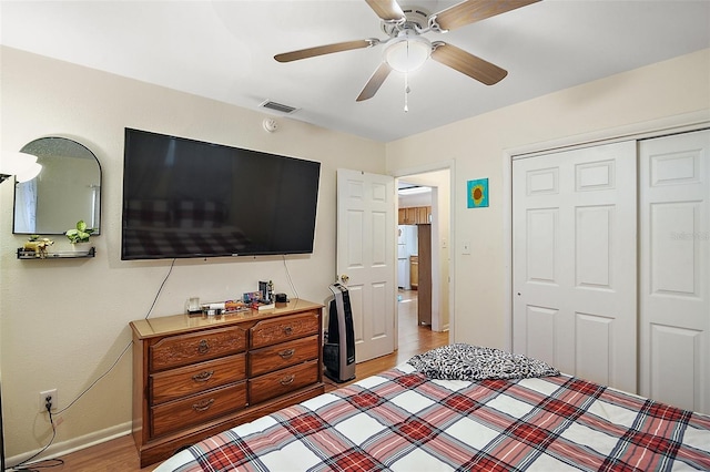 bedroom with white fridge, a closet, light hardwood / wood-style flooring, and ceiling fan