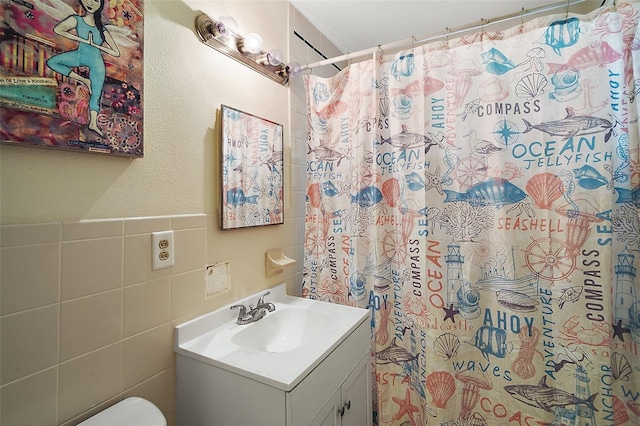 bathroom with toilet, a shower with shower curtain, tile walls, and vanity