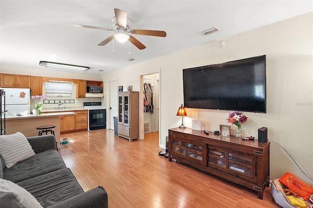 living room featuring ceiling fan, sink, and light hardwood / wood-style floors