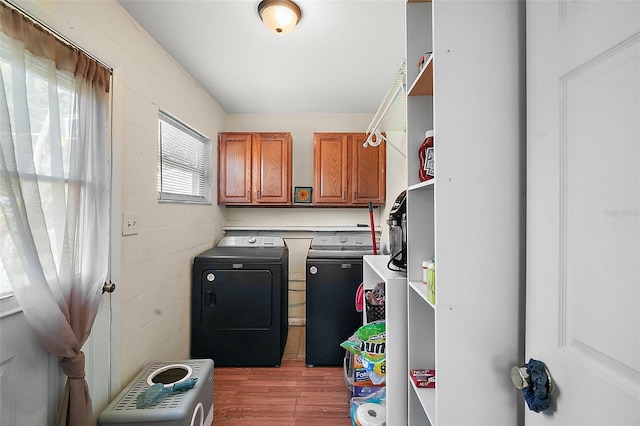 washroom with washer and clothes dryer, wood-type flooring, and cabinets