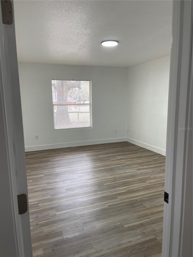 empty room featuring dark hardwood / wood-style floors and a textured ceiling