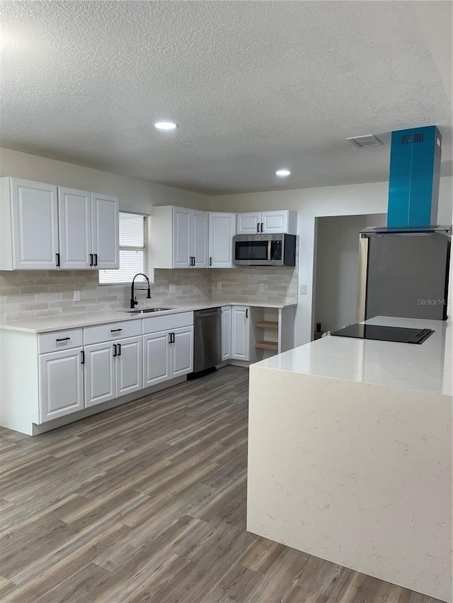 kitchen featuring hardwood / wood-style floors, sink, white cabinets, stainless steel appliances, and a textured ceiling