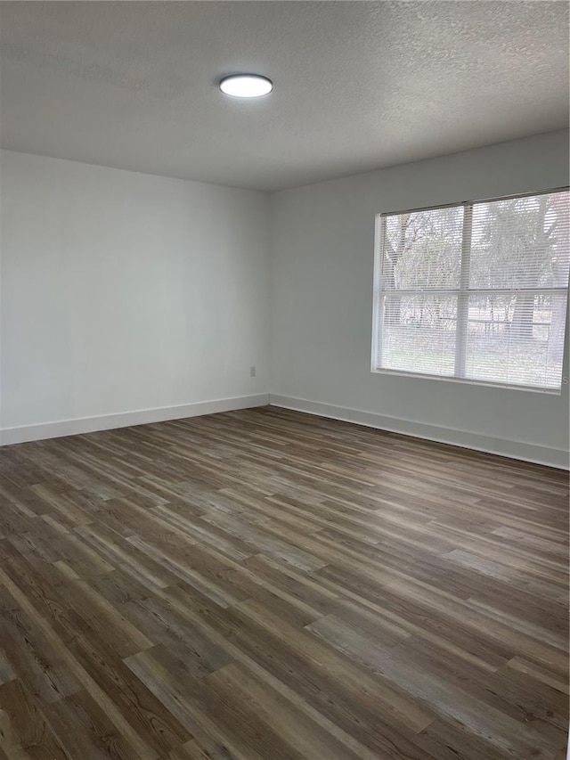 unfurnished room featuring dark hardwood / wood-style floors and a textured ceiling