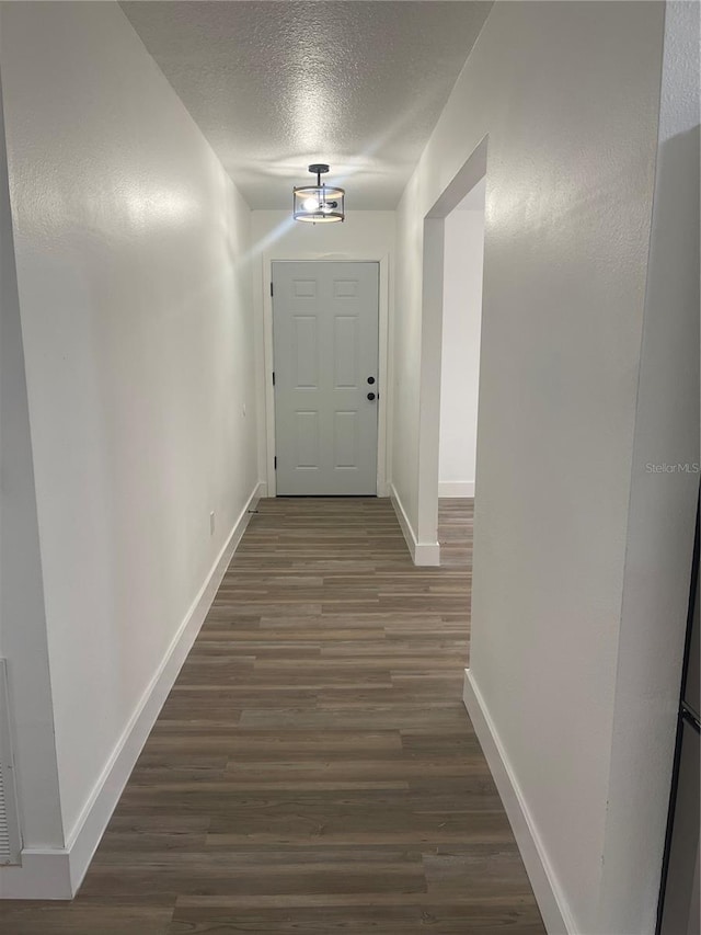 hall featuring dark wood-type flooring and a textured ceiling