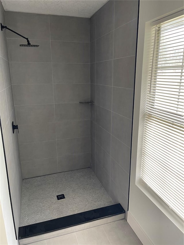 bathroom with a tile shower and tile patterned floors