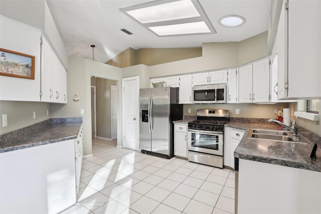 kitchen with a sink, dark countertops, vaulted ceiling, and stainless steel appliances