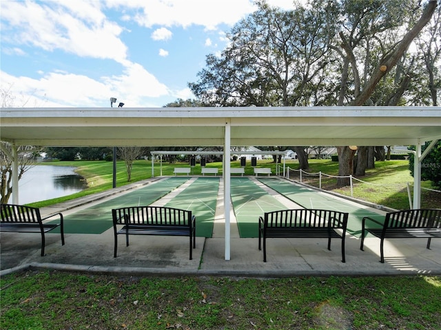 view of community with shuffleboard, a yard, and a water view