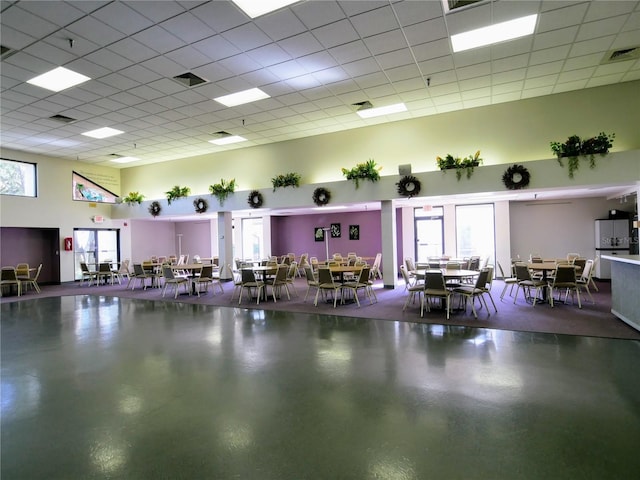 interior space with concrete floors, a drop ceiling, visible vents, and a towering ceiling