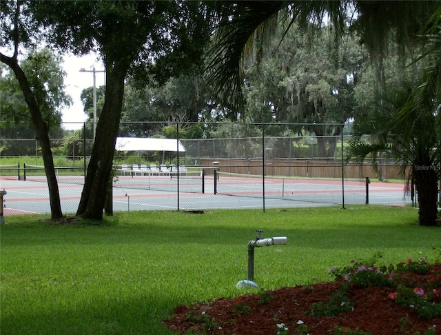 view of sport court with a lawn and fence