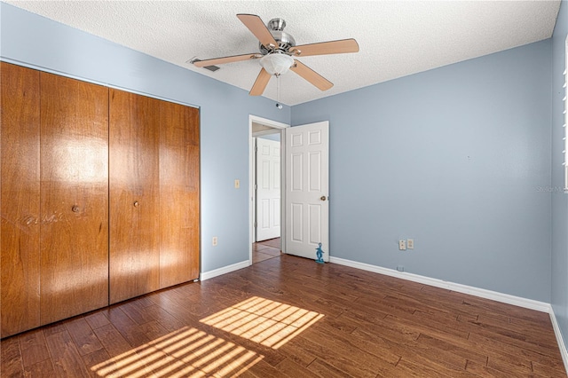 unfurnished bedroom with ceiling fan, dark wood-type flooring, a textured ceiling, and a closet