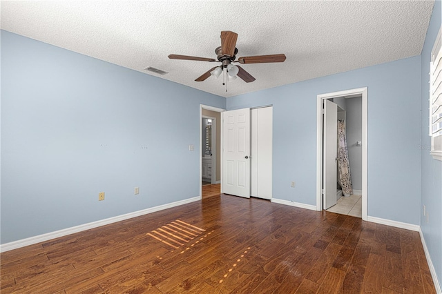 unfurnished bedroom with ceiling fan, hardwood / wood-style floors, ensuite bathroom, and a textured ceiling