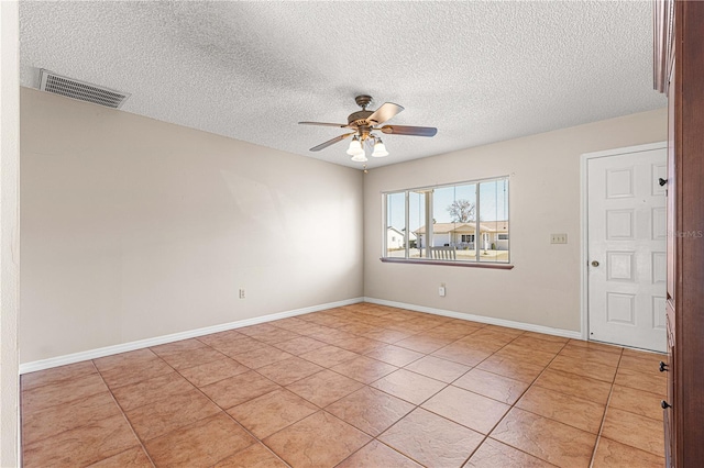 spare room featuring a textured ceiling, light tile patterned floors, and ceiling fan