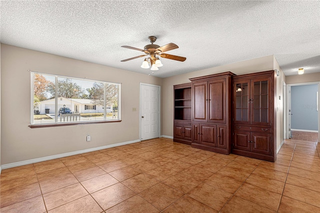 empty room featuring ceiling fan, a textured ceiling, and light tile patterned flooring